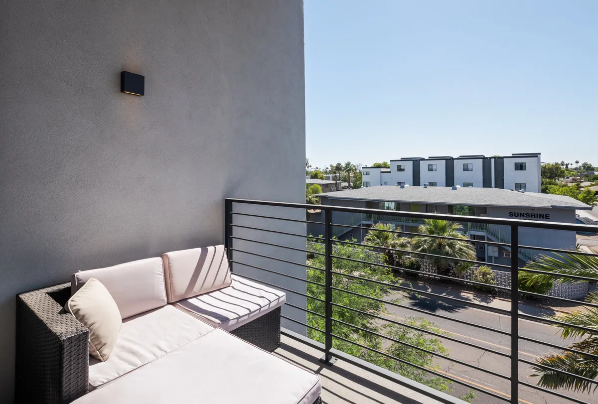 A tranquil private balcony with comfortable seating and railing, offering vistas of surrounding buildings. It’s a peaceful retreat that brings the energy of Old Town Scottsdale close while providing fresh air and views.