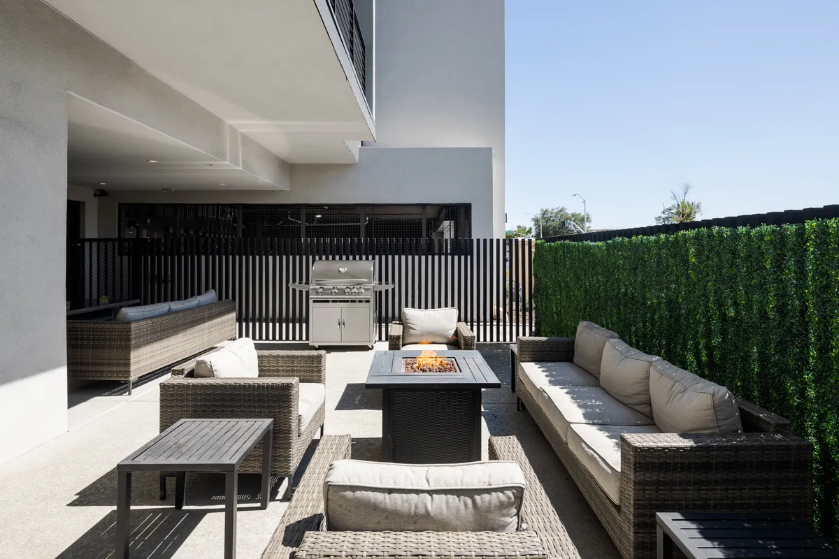 A cozy outdoor communal area with comfortable seating, a fire pit, built-in grill, and well-tended greenery. The scene radiates warmth and encourages social gatherings, barbecues, and evenings by the fire.