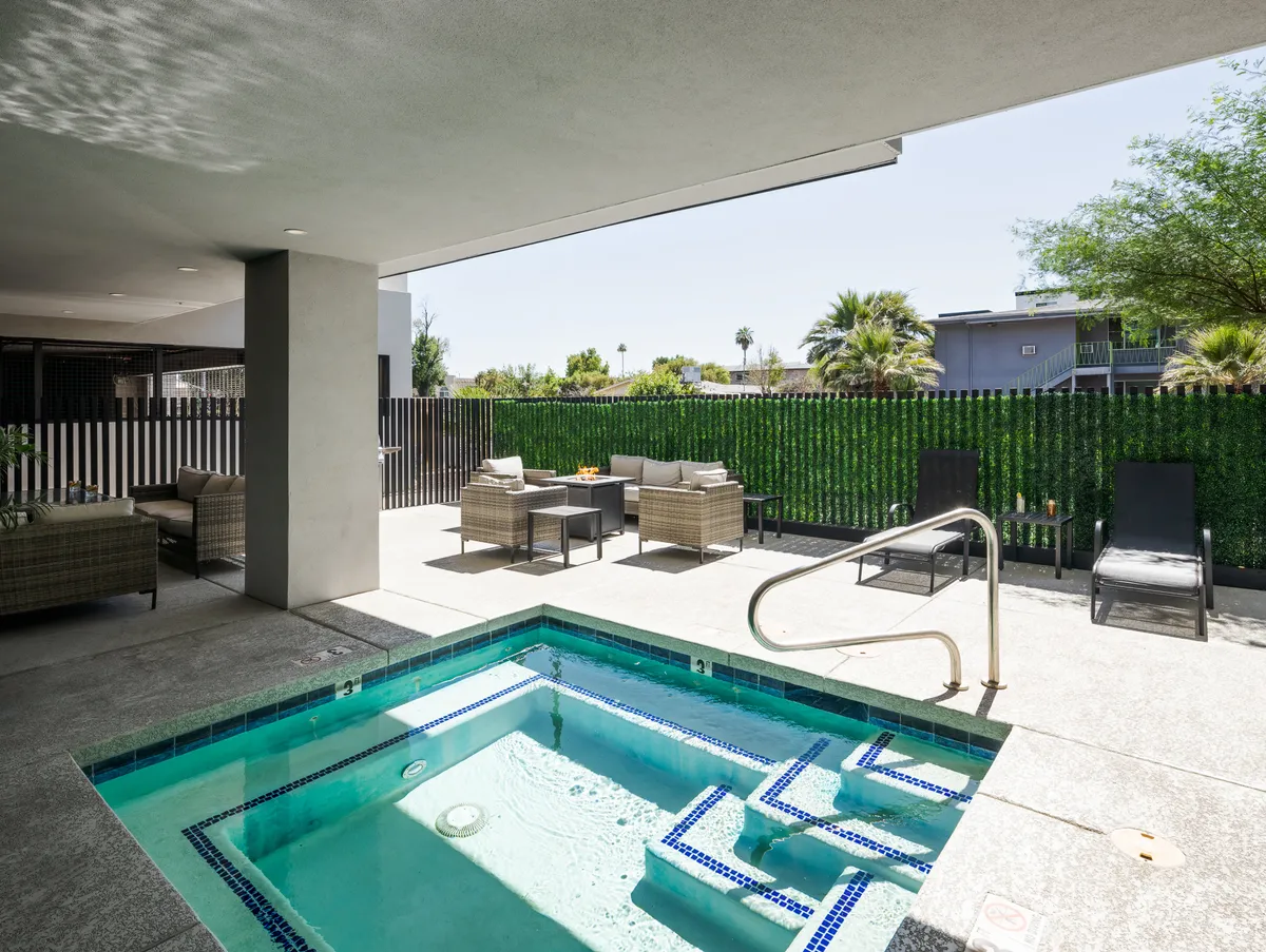 An inviting outdoor area showcasing a spa pool (hot tub) surrounded by lush greenery and outdoor seating, all framed by a secure fence. The setting exudes tranquility and relaxation, perfect for unwinding after a day of activity.