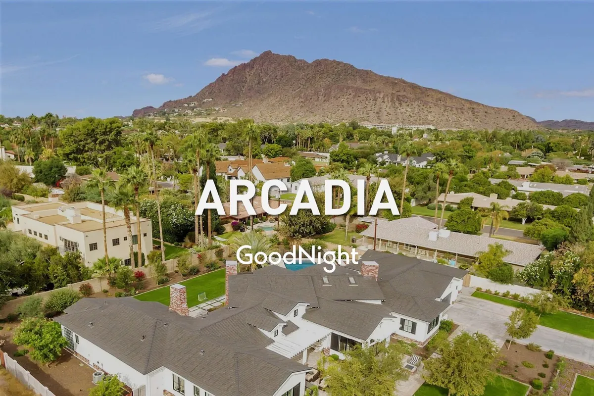 An inviting exterior shot of a spacious home framed by lush greenery, palm trees, and a mountain backdrop. The setting is serene and welcoming, ideal for relaxing outdoor gatherings or morning coffee after a night out.